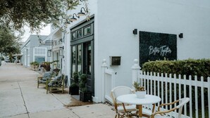 A white building with a sign reading 'Better Together,' outdoor seating with chairs and tables, and a white picket fence. - THE PINK ROOM @emilysontheisland (Galveston)
