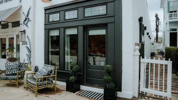 A building with a dark facade, large windows, and a sign reading 'The Pink Room.' - THE PINK ROOM @emilysontheisland (Galveston)