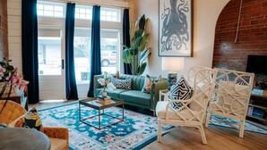 A living room with a sofa, coffee table, and wicker chairs, a large plant, and a fireplace. - THE PINK ROOM @emilysontheisland (Galveston)