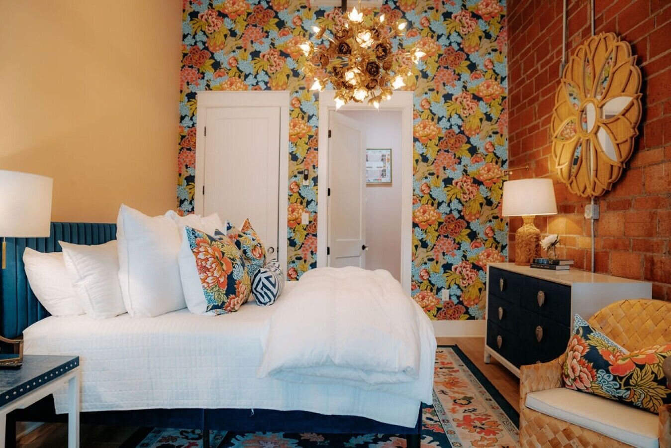 A bedroom with a bed, bedside tables, a dresser, a chair, a chandelier, and a mirror.