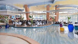 A spacious indoor area with a central pool, multiple dining tables, and large windows allowing natural light. - 2 and 3 Bedroom Apartments within Crown Towers (Surfers Paradise)