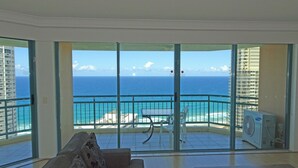 A balcony with a view of the ocean, a white couch, and a table. - 2 and 3 Bedroom Apartments within Crown Towers (Surfers Paradise)