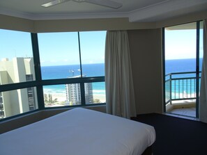 Quarto de hotel com uma janela grande que oferece vista para o oceano e um edifício em construção.