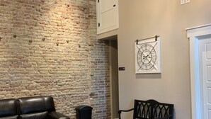 A room with a brick wall, a round table, two black sofas, and a bench. - Park Hotel (Clarkdale)
