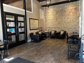Um interior acolhedor, com parede de tijolos, poltronas de couro e chão de madeira.