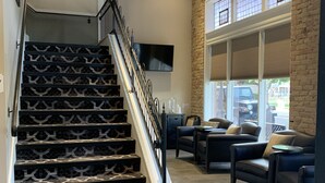 A staircase with patterned steps leading to a landing, a seating area with leather sofas, and a large window with blinds. - Park Hotel (Clarkdale)