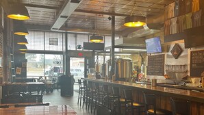 A restaurant interior with a bar area, high ceiling with decorative panels, and a view of the outside. - Park Hotel (Clarkdale)