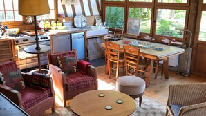 Eine rustikale Küche mit Holzbalken, einem Essbereich mit rundem Tisch und einer gemütlichen Sitzecke.