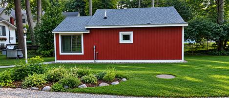 A red single-story house with a sloped roof, a small window, and a chimney.