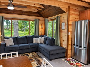 Een modern chalet interieur met een hoekbank, een eettafel en een roestvrijstalen koelkast.