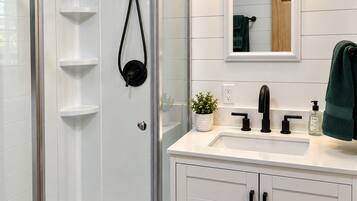 A modern bathroom with a glass-enclosed shower, a white vanity with a sink, and a mirror above.