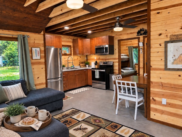 A cabin interior with a kitchenette, dining area, and a sofa with a tray of breakfast items.