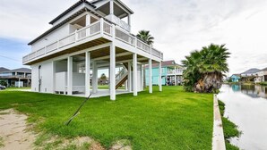 A two-story house with a balcony, a staircase leading to the upper floor, and a small garden area. - 'Saltwater Therapy' Luxurious Beach House Rental (Bolivar Peninsula)