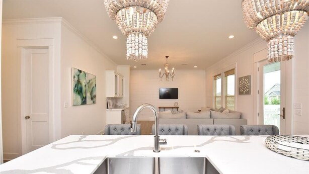 A modern kitchen with a central island, stainless steel sink, and two chandeliers. - 'Saltwater Therapy' Luxurious Beach House Rental (Bolivar Peninsula)