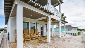 A wooden deck with outdoor seating, a covered porch, and a view of the ocean. - 'Saltwater Therapy' Luxurious Beach House Rental (Bolivar Peninsula)
