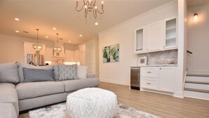 A modern living room with a sofa, ottoman, and chandelier. - 'Saltwater Therapy' Luxurious Beach House Rental (Bolivar Peninsula)