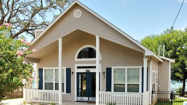 Une maison de plain-pied avec un porche à l’avant, un garage et une pelouse bien entretenue.