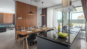 Una cocina moderna con una isla central, comedor con sillas y vistas al exterior.