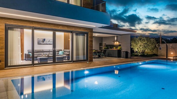 Una casa moderna de dos pisos con piscina, comedor y cocina.