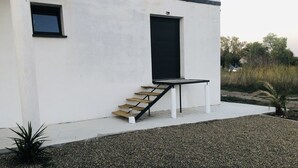 A modern building with a white exterior, a black door, and a small window. - U PRIMU - Spacious, quiet apartment Aléria (Aléria)