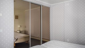 A bedroom with a bed, a nightstand, a lamp, and a sliding door leading to another room.