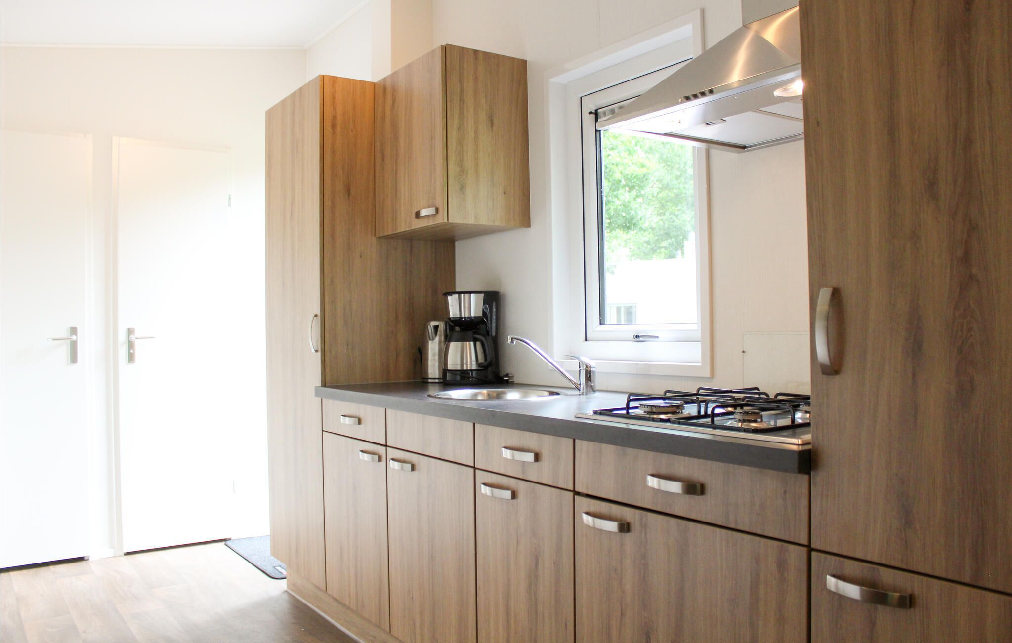 A modern kitchen with wooden cabinets, a stainless steel sink, and a gas stove.