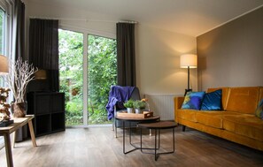 Relax in this stylish living room with a sofa, table, and chair, surrounded by natural light and a decorative vase.