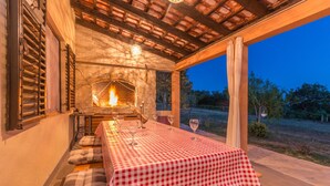 Un espace de restauration en plein air avec une nappe à carreaux, une cheminée en pierre et une vue sur le paysage environnant.
