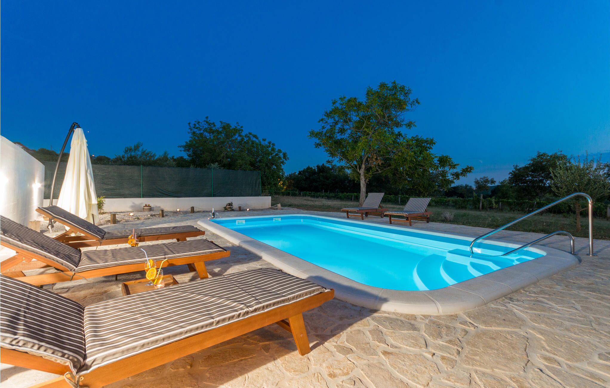 A swimming pool with lounge chairs and a sun umbrella.