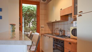 A compact kitchen with a dining area, a view through the door, and a microwave on the counter. - Lovely apartment in Marina di Ragusa with WiFi (Marina di Ragusa)