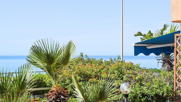 A coastal view with a clear sky, a blue umbrella structure, and a street lamp. - Lovely apartment in Marina di Ragusa with WiFi (Marina di Ragusa)