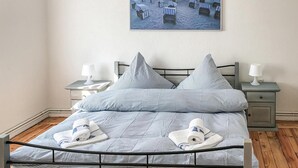 A neatly made bed with striped bedding, two bedside tables with lamps, and a framed picture of beach chairs on the wall. - 3 bedroom stunning home in Alt Bukow (Alt Bukow)