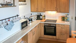 A compact kitchen with wooden cabinets, a microwave, a toaster, and a stove. - 3 bedroom stunning home in Alt Bukow (Alt Bukow)