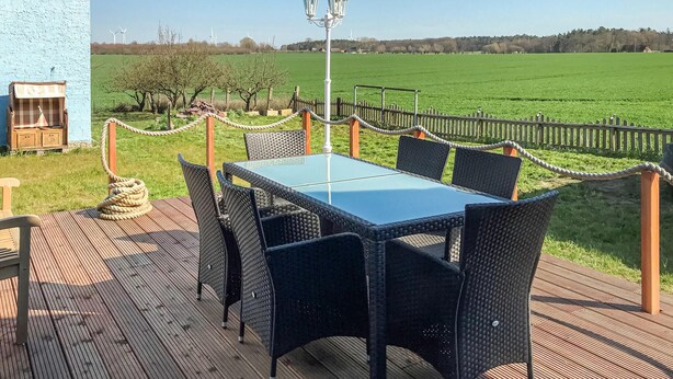 A deck with a table and chairs, a lamp post, and a rope barrier. - 3 bedroom stunning home in Alt Bukow (Alt Bukow)