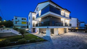 Una moderna casa a due piani con un ampio giardino anteriore e un vialetto coperto.