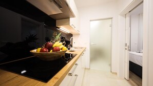 Una cucina moderna con un piano di lavoro in legno, una ciotola di frutta, una moka e un fornello.