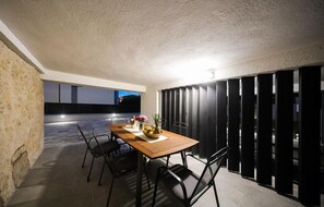 An outdoor dining area with a wooden table and chairs, a bowl of fruit, and a vase of flowers. - Amazing apartment in Zadar (Zadar)