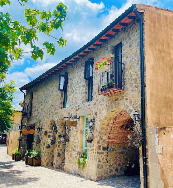 A stone building with multiple windows, some with flower boxes, and a sign indicating a restaurant.