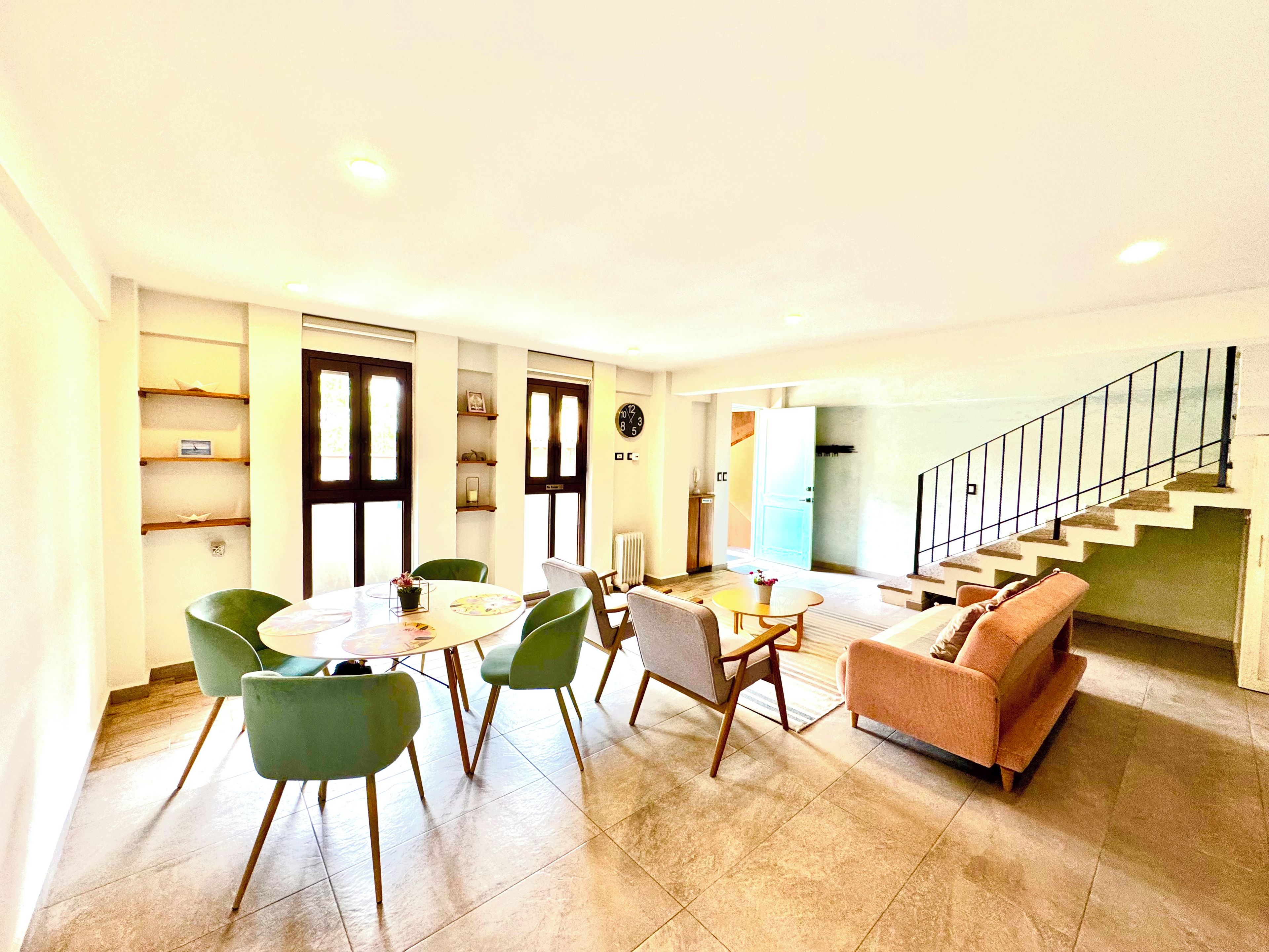 Un salon moderne comprenant un canapé, des fauteuils, une table à manger et un escalier.