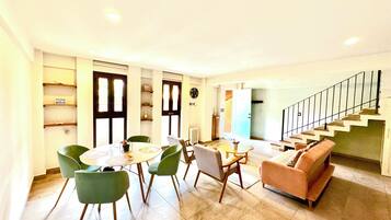 Un salon moderne comprenant un canapé, des fauteuils, une table à manger et un escalier.