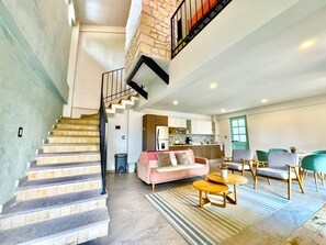 A modern interior with a staircase, living room, kitchen, and dining area.