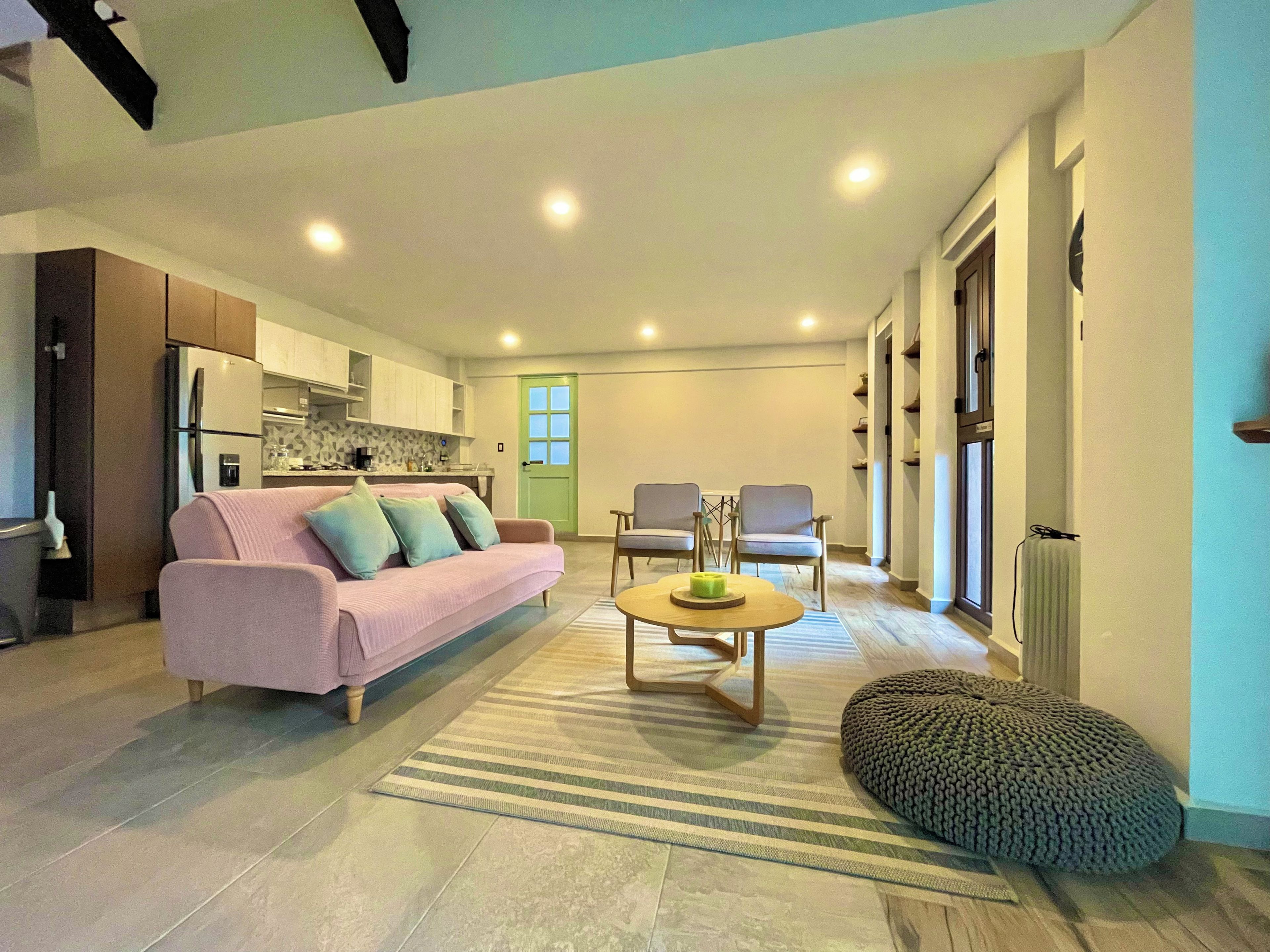 Een moderne woonkamer met een bank, stoelen, een salontafel en een keuken op de achtergrond.