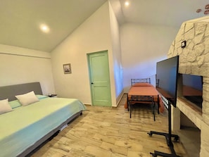 Een kamer met een bed, een bureau, een televisie en een deur.