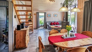 A cozy cabin interior with a wooden staircase, a dining area with a red tablecloth, and a sofa with red cushions. - Amazing home in Rechlin with kitchen (Rechlin)