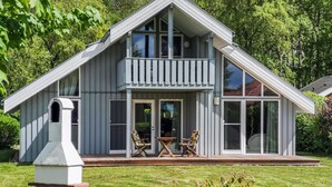 A two-story house with a balcony, large windows, and a wooden deck. - Amazing home in Rechlin with kitchen (Rechlin)