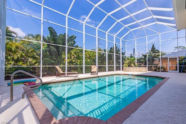 An indoor swimming pool with a glass ceiling, surrounded by palm trees and a clear blue sky. - Beautiful 4 bedroom, 3 bath w/ heated swimming pool home 14 mins from the beach (Bonita Springs)