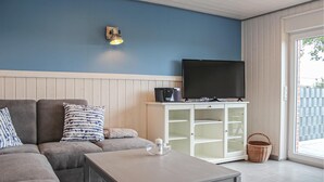 Een woonkamer met een bank, een salontafel, een kast met een flatscreentelevisie en een mand.