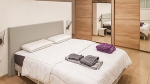 A neatly made bed with white bedding and pillows, a stack of folded clothes, and a purple towel on the bed. - Stunning home in Salles d'Aude (Salles d'Aude)
