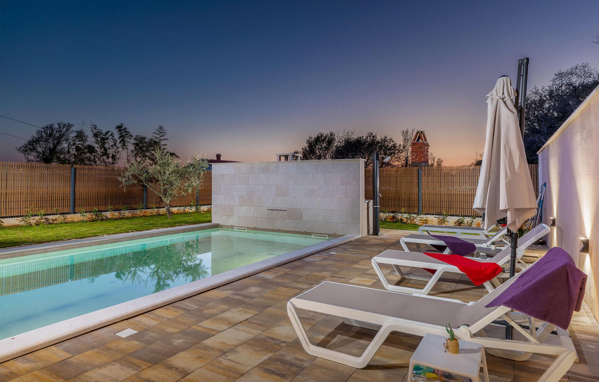 A swimming pool with lounge chairs and a covered area.