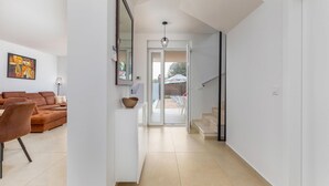 Et moderne interiør med en sofa, spisebord og stole i opholdsstuen, en trappe og udsigt til terrassen.